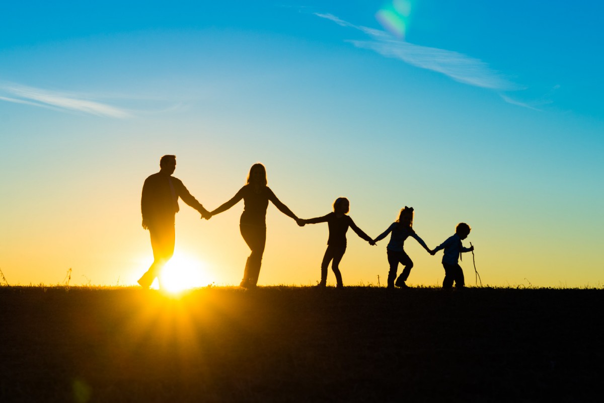 een familie bij de zon die ondergaat