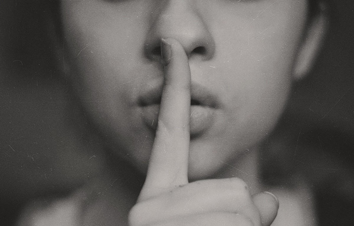 een vrouw houdt een vinger voor haar lippen