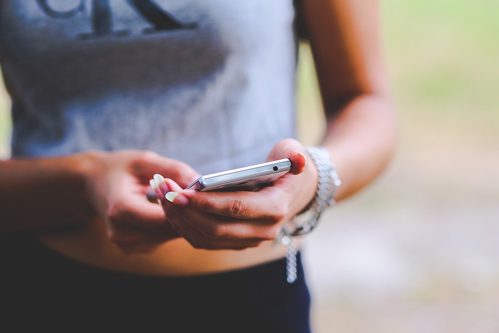 een tiener met een smartphone in de hand